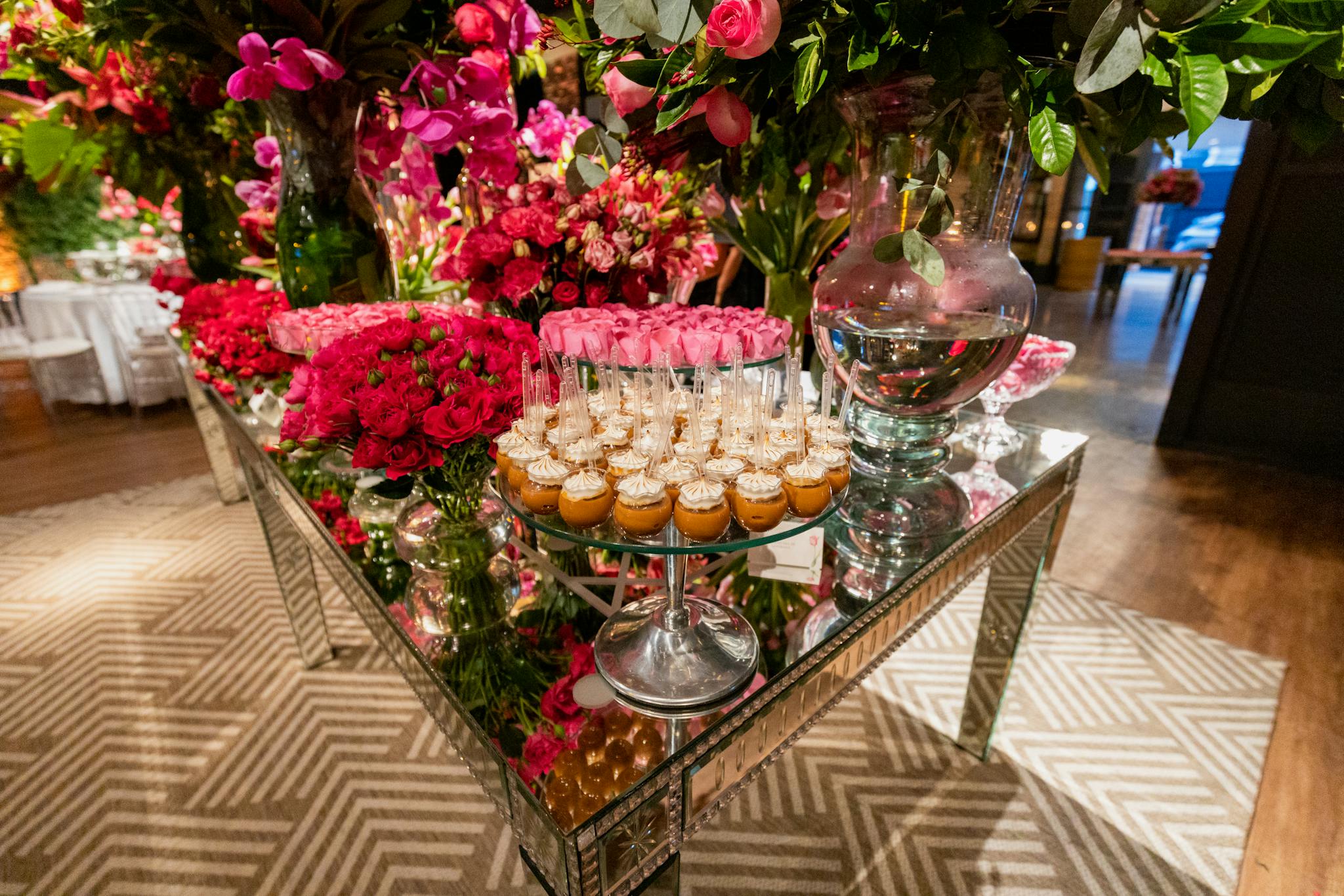 A beautifully decorated table with vibrant flowers and desserts at an indoor wedding reception.