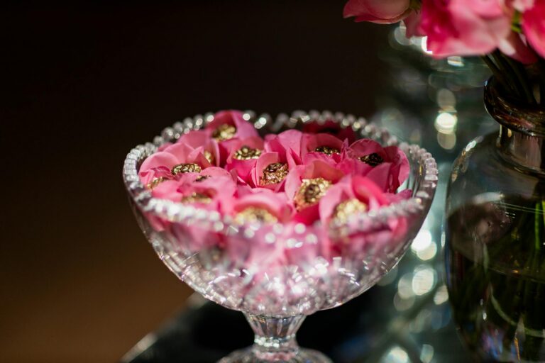 Elegant crystal bowl filled with pink flower-shaped decorative confections for events.