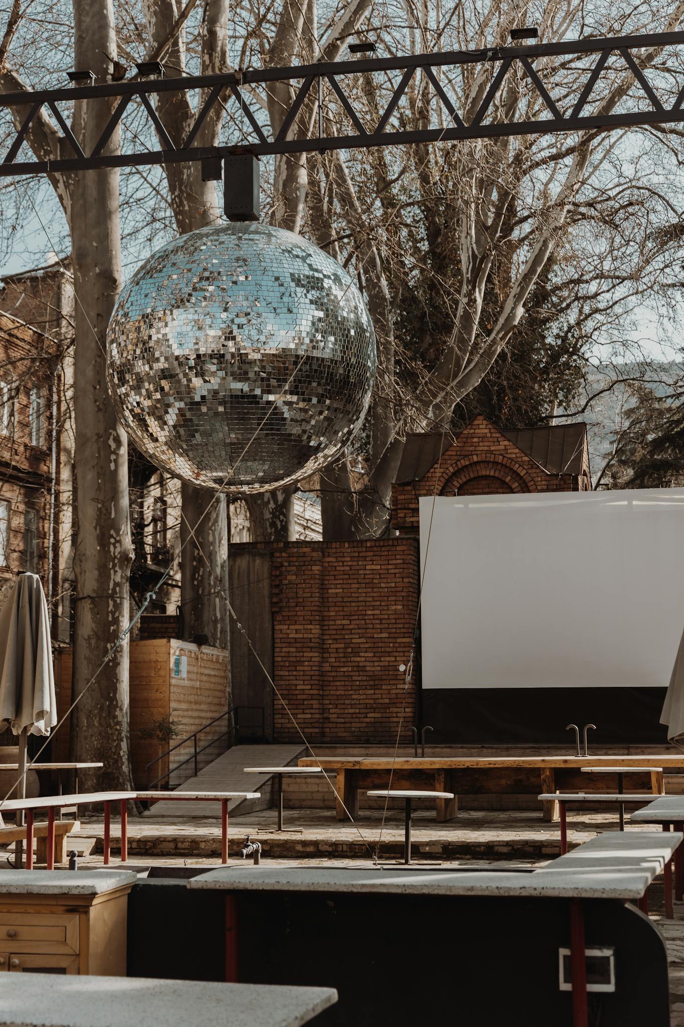 Outdoor café with disco ball, empty seating, and a street view, perfect for urban nightlife themes.